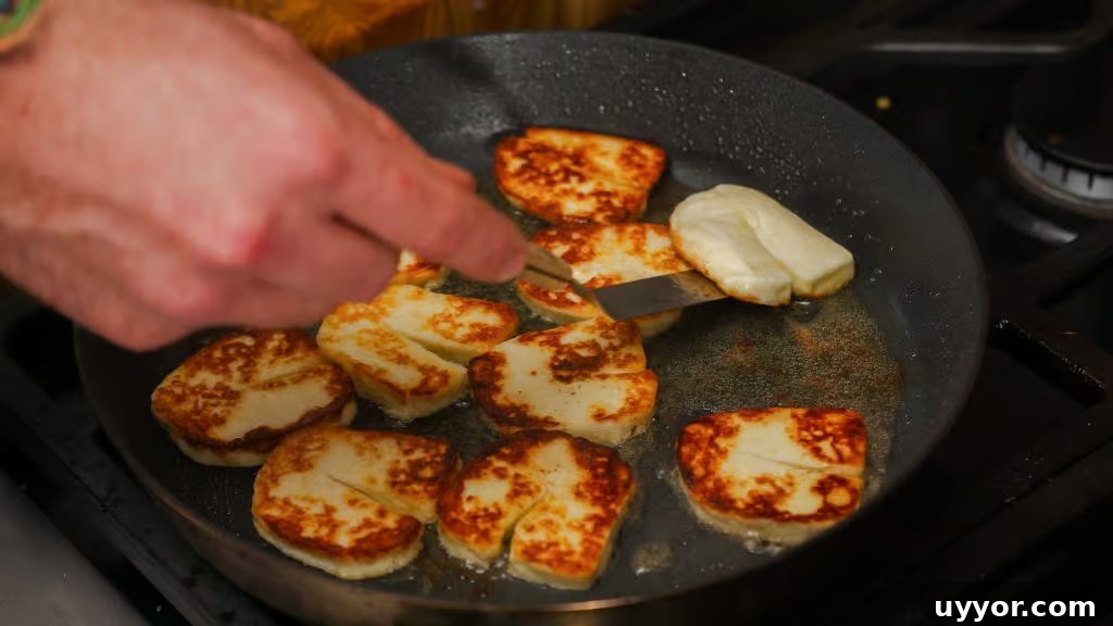 Halloumi being flipped and fried in a pan. 