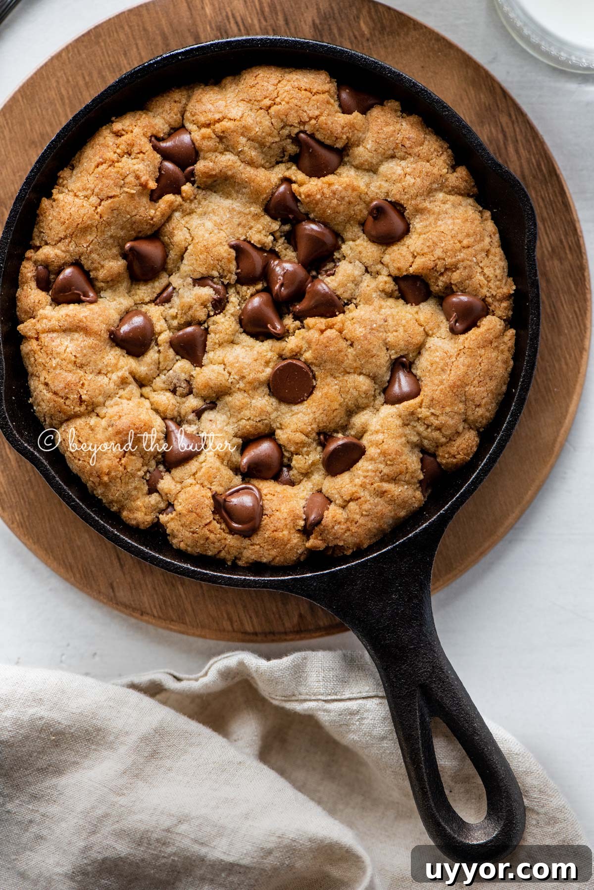Just baked chocolate chip skillet cookies on light gray background with cloth napkin | All Images © Beyond the Butter®