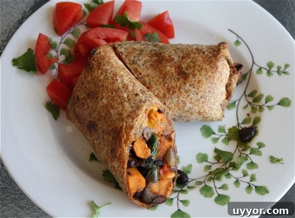 Savory sweet Roasted Veggie and Black Bean Burritos are a delicious vegetarian meal even meat lovers will enjoy! veggie and black bean burrito cut in half on a white plate