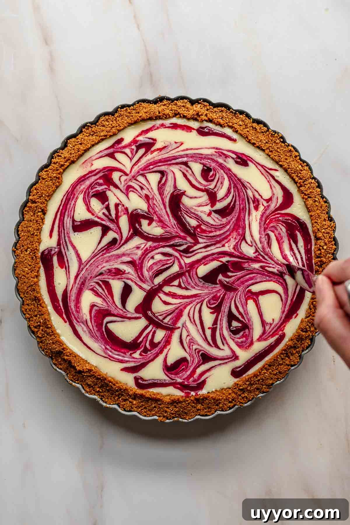 A knife swirls the cranberry puree through the white chocolate.