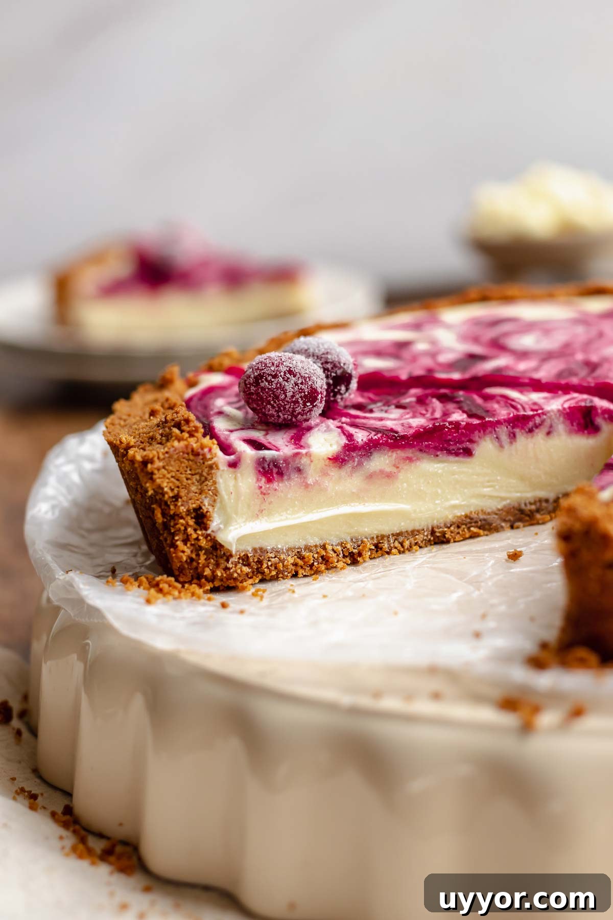 A cross section of a white chocolate tart with sugared cranberries on top.
