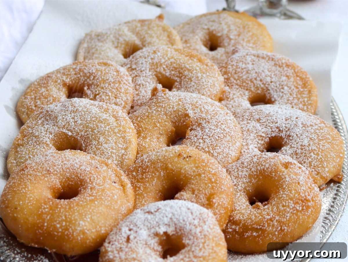 25 Cozy Apple Recipes That Capture Fall Flavors 14 vegan apple fritters on a silver platter with powdered sugar