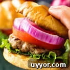 Hand holding a grilled burger with toppings