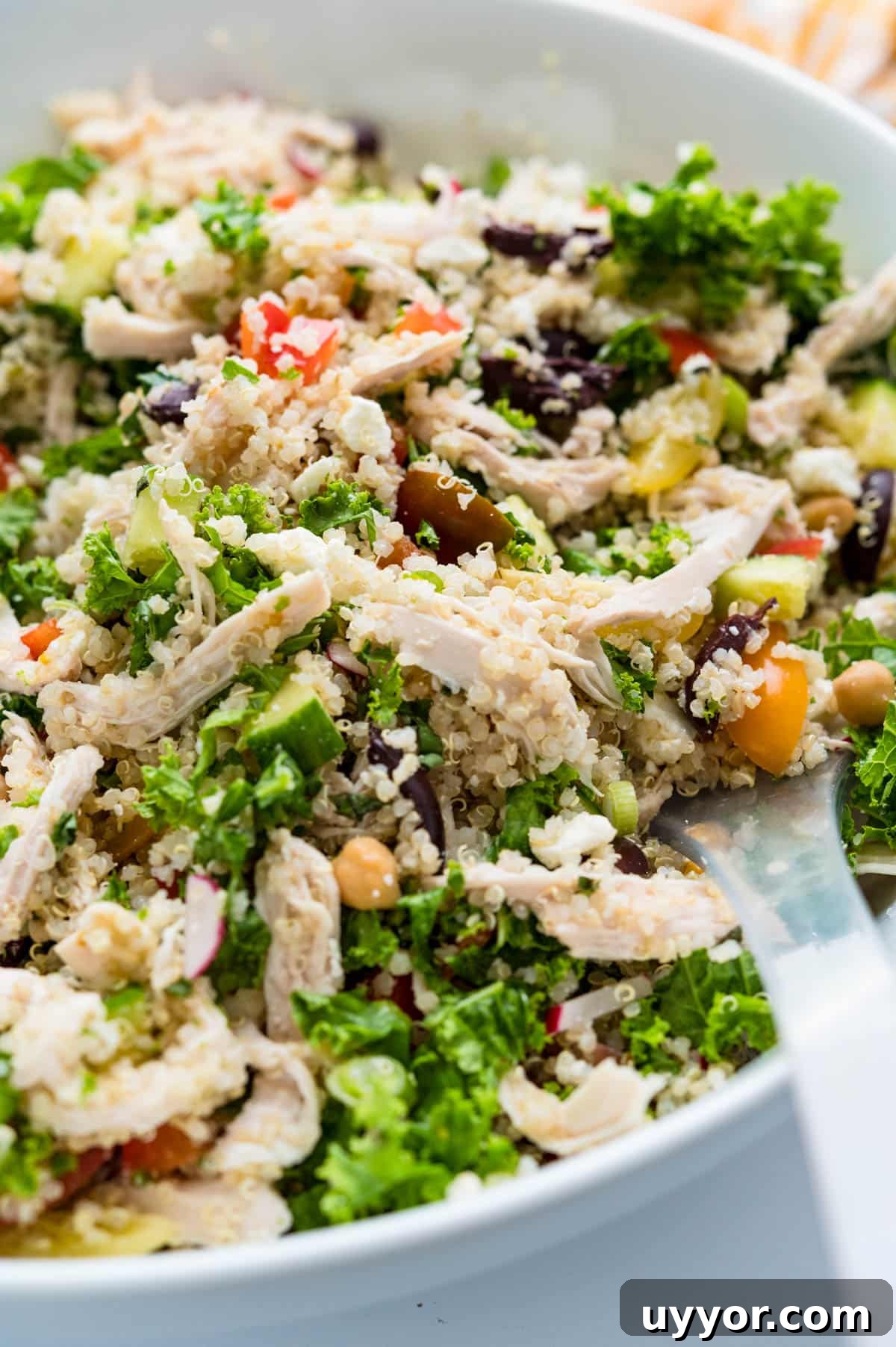 tossing the Mediterranean Chicken Quinoa salad with the dressing.