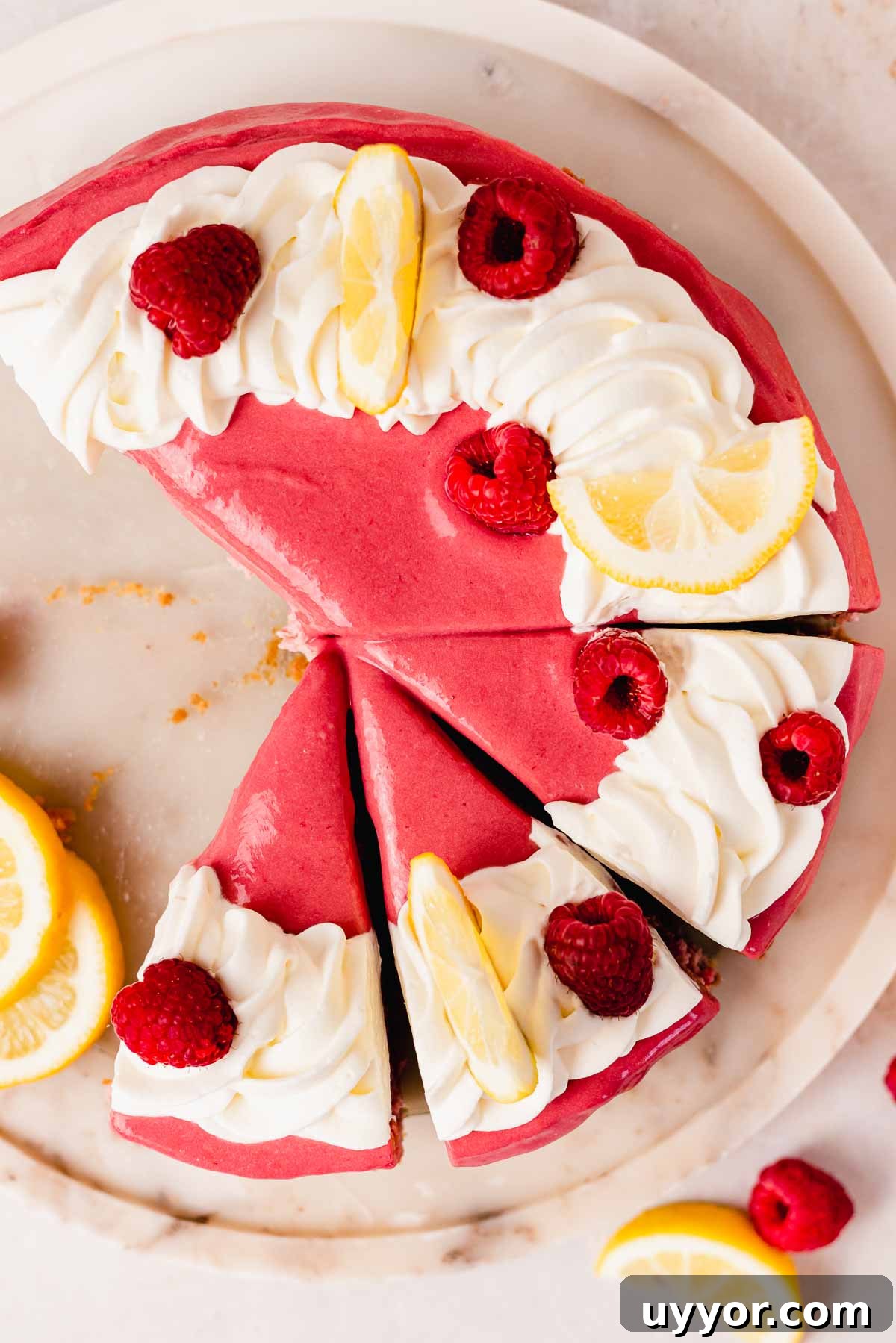 Lemon Raspberry Cheesecake Recipe: Zesty Citrus Cheesecake with Fresh Berries 4 sliced lemon raspberry cheesecake with whipped cream swirl, lemon wedges, and whole raspberries