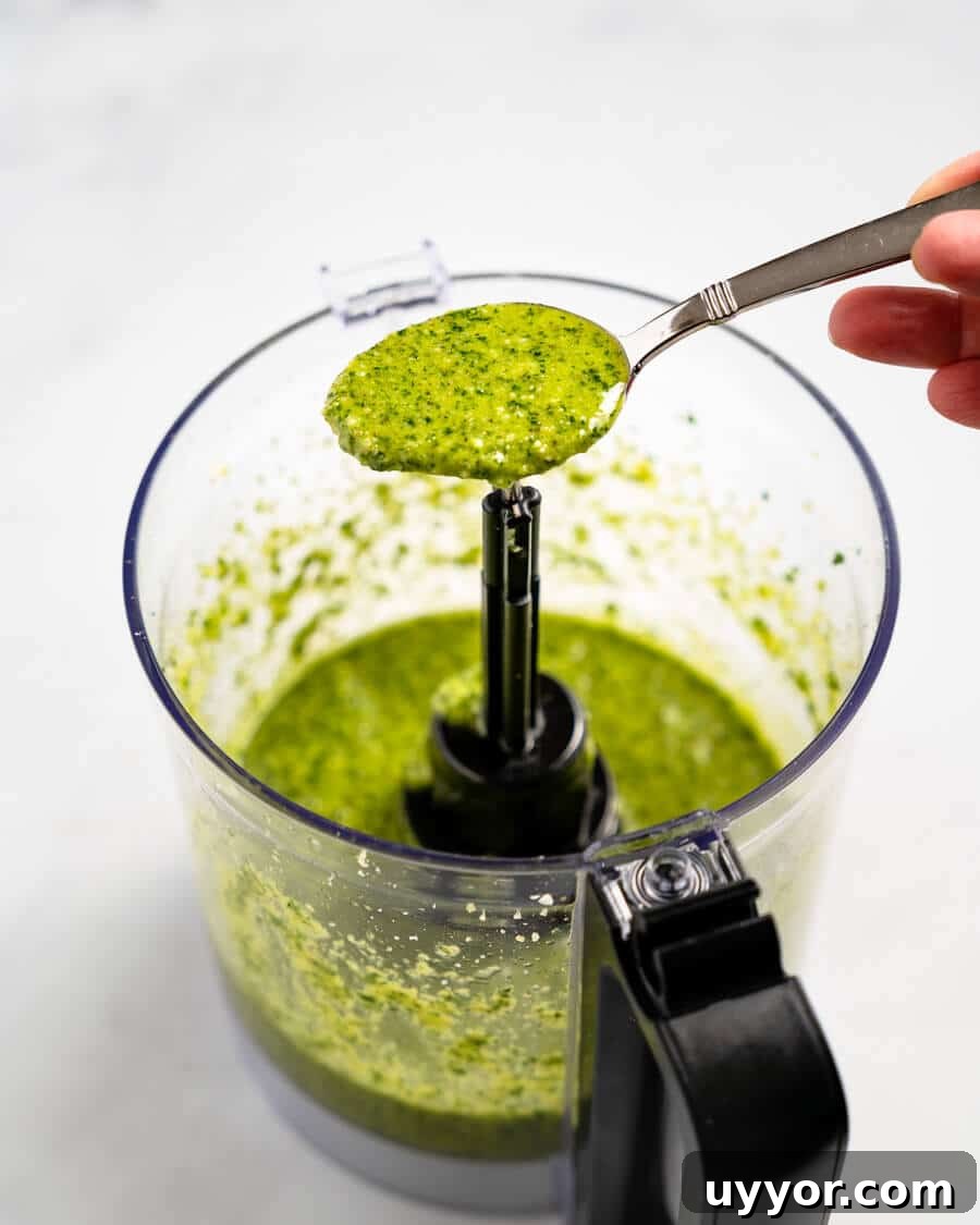 Spoonful of cilantro pesto sitting over a food processor