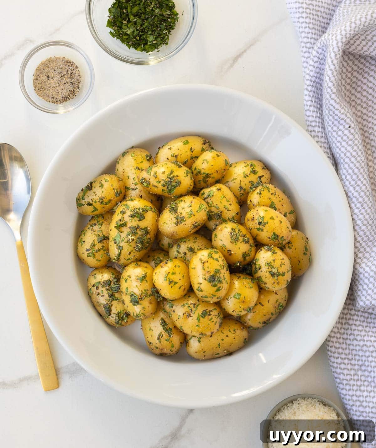 Buttery Baby Dutch Yellow Potatoes Recipe for Tender Roasted Spuds 7 Herbed baby potatoes in a white bowl at the table for serving.