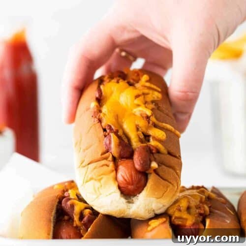 Ultimate Chili Cheese Dog Recipe: Loaded Classic Hot Dog 2 hand holding chili cheese dog