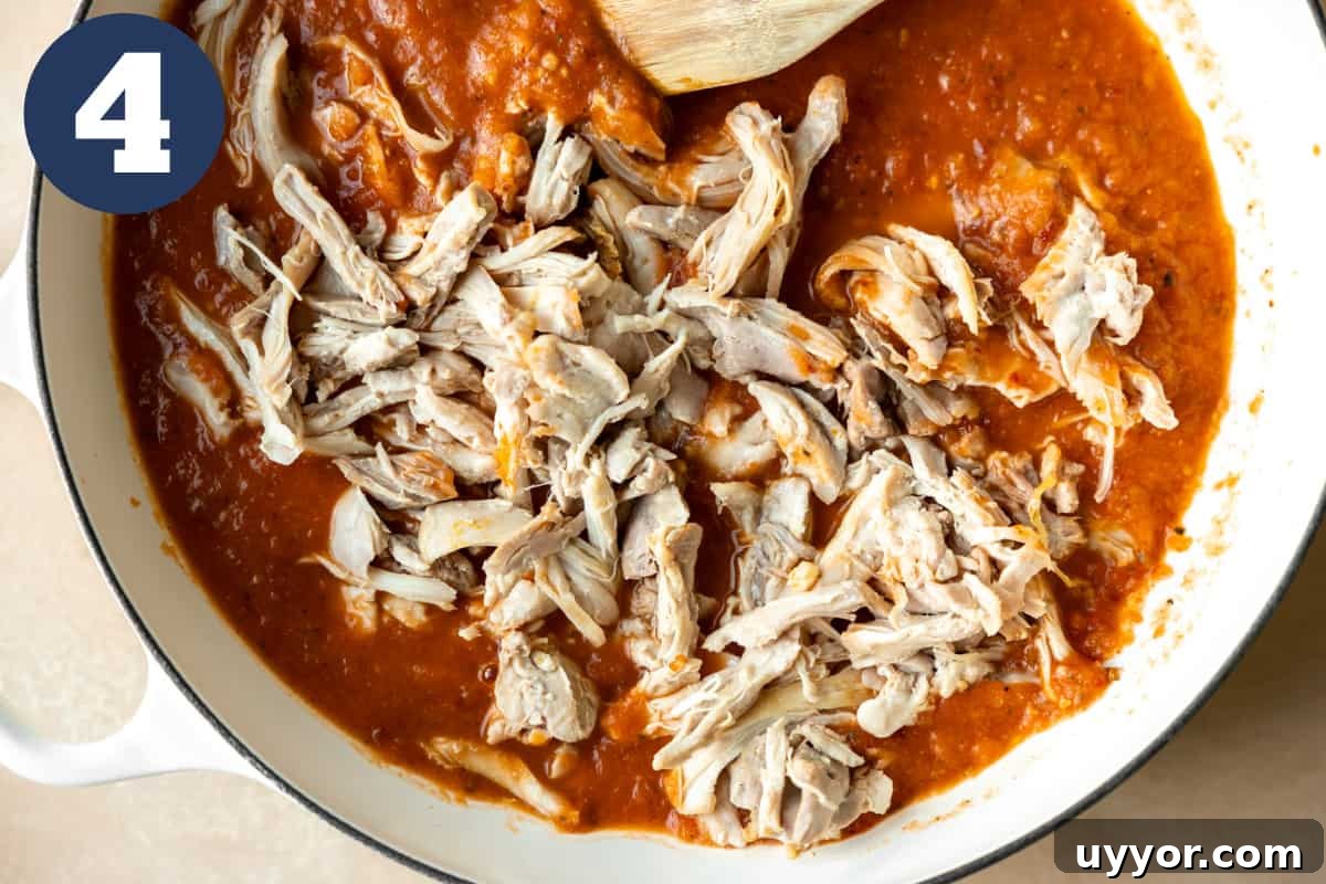 Authentic Chicken Tinga Recipe: Smoky Mexican Shredded Chicken 6 Shredded chicken added into a red chipotle sauce for simmering.