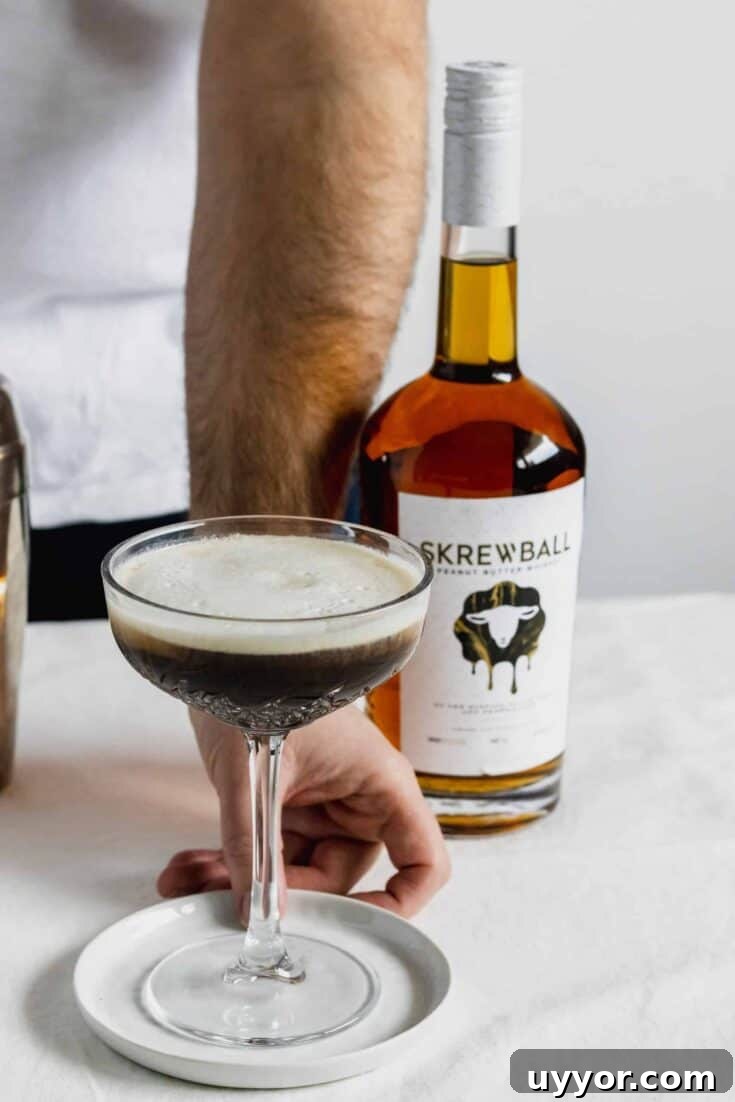 A peanut butter vanilla espresso whiskey martini next to a bottle of Skrewball.