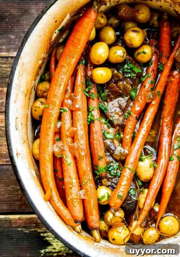 Balsamic Dijon Chuck Roast: Flavorful Pot Roast Recipe 2 Overhead view of a Dutch oven filled with tender chuck roast, whole carrots, and baby potatoes