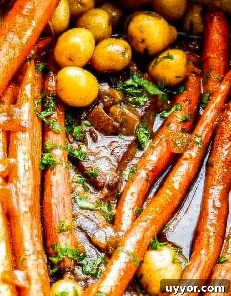 Balsamic Dijon Chuck Roast: Flavorful Pot Roast Recipe 5 Tight close-up of glazed carrots and potatoes nestled in savory pot roast drippings as part of a chuck roast recipe