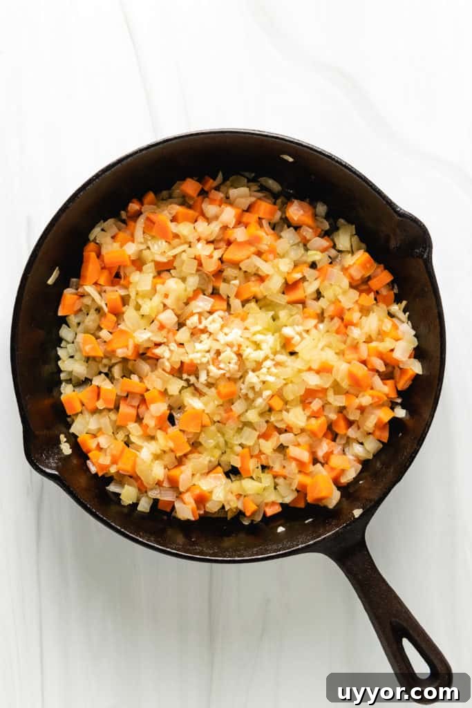 Top down view of carrots, onions, and garlic in cast iron.