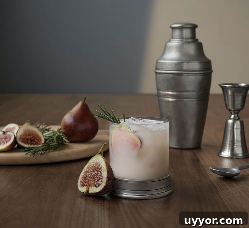 Balsamic Fig Shrub Recipe with Fresh Figs for Cocktails and Dressings 3 Fig shrub cocktail in a glass with a slice of fresh fig and a sprig of rosemary.