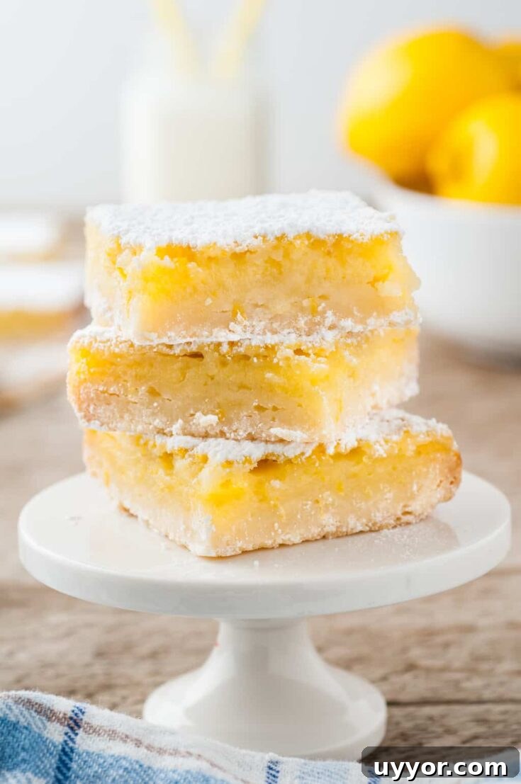 three lemon bars stacked on top of a white cake stand