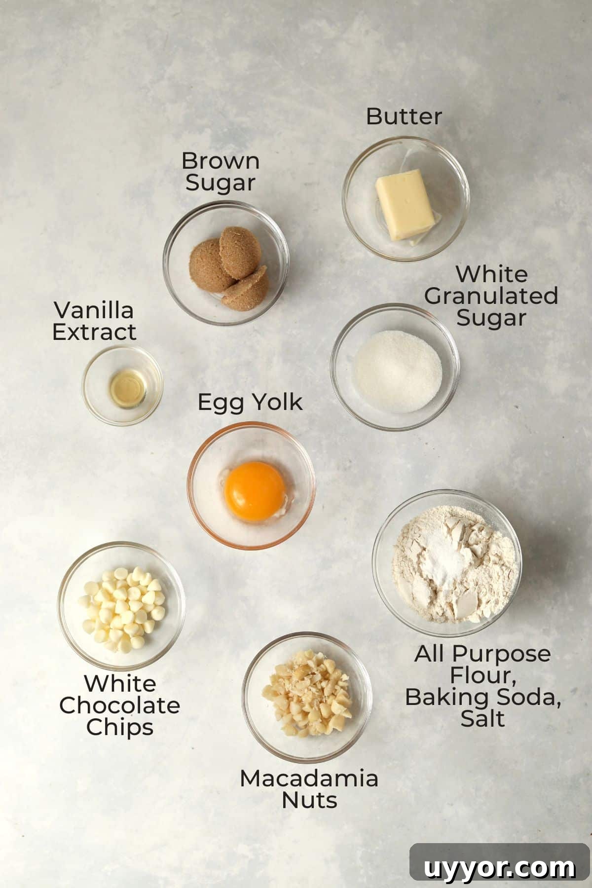 Ingredients to make a small batch of white chocolate macadamia nut cookies in small glass prep bowls.