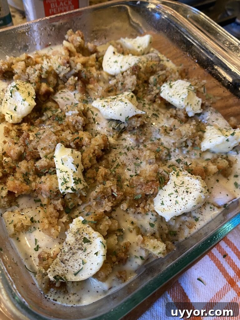 Creamy-Gravy Stuffed Turkey Roll-Ups for Holiday Dinner 8 The turkey roll ups in a baking dish covered with stuffing and butter
