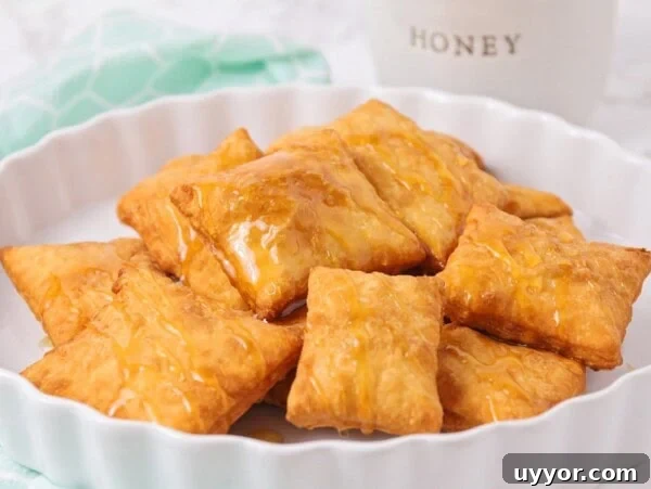 Several sopapillas on a platter drizzled with honey.