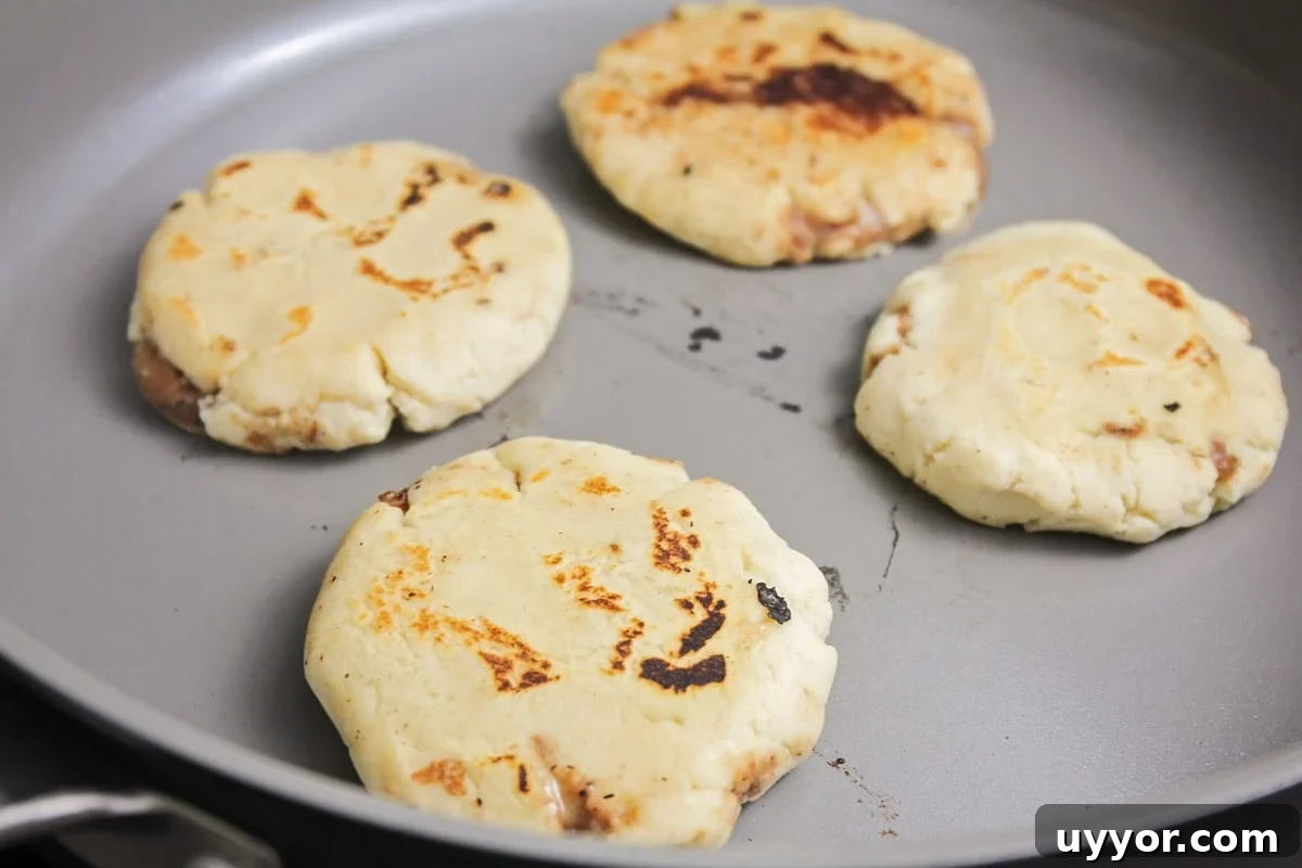 Pupusas being fried in skillet.