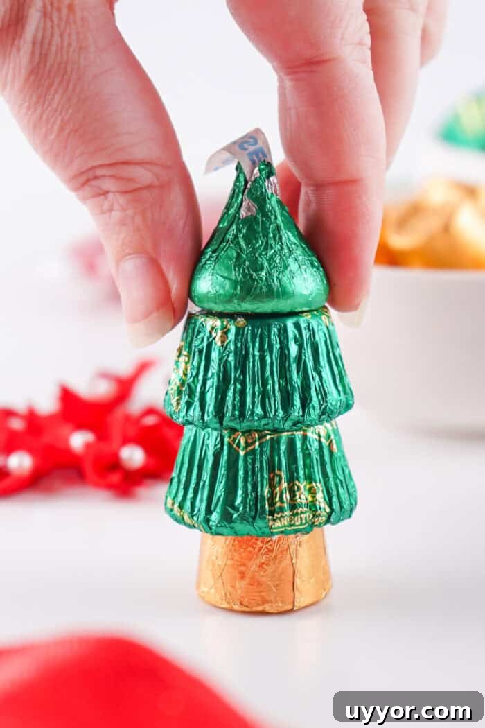 These Reese's Peanut Butter Cup Christmas Trees are so fun and easy to make. topping the candy tree with a Hershey's Kiss