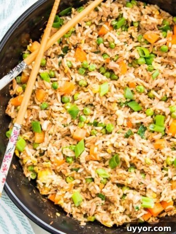 A pan filled with tuna fried rice with chop sticks on top.