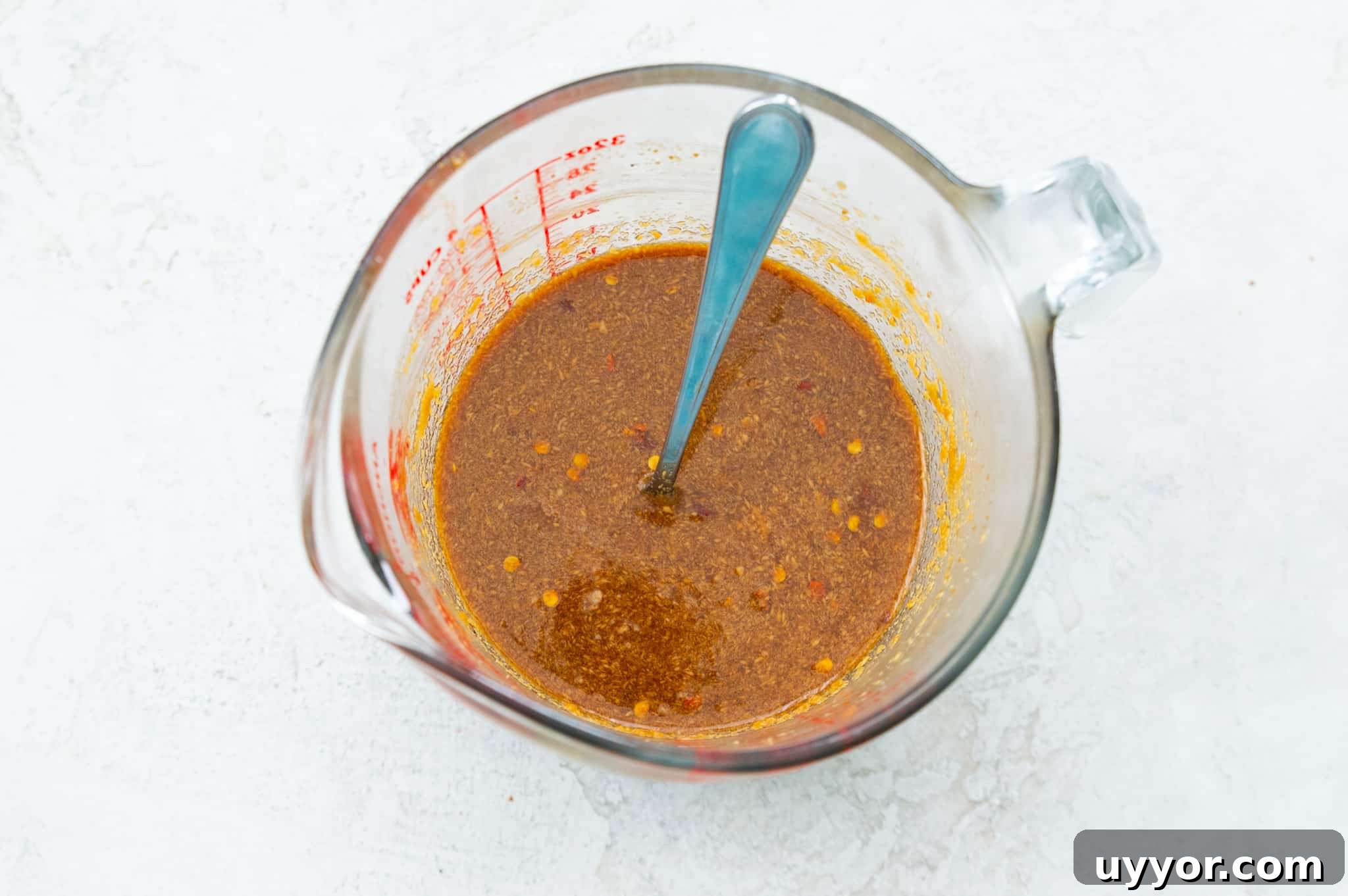 A glass measuring cup with a peanut sauce in it.