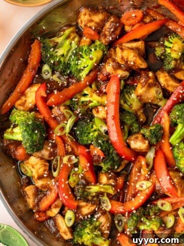 A pan filled with a chicken and vegetable stir fry with broccoli and chopped bell peppers.