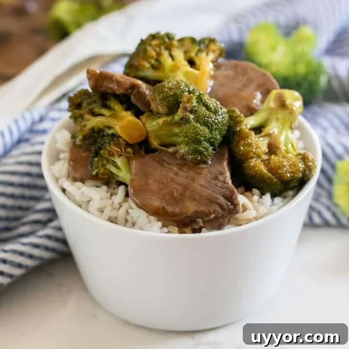 A white bowl with white rice and beef and broccoli on top with a blue and white striped napkin next to it.