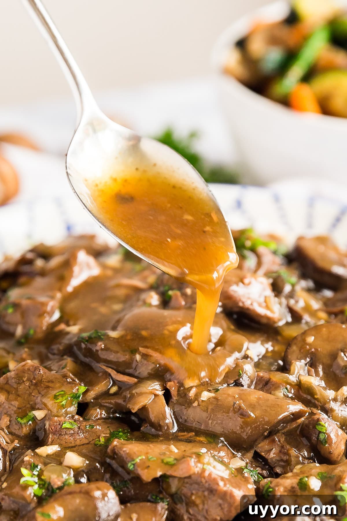Instant Pot Beef Tips with Rich Mushroom Gravy 3 A spoon pouring gravy over beef tips.