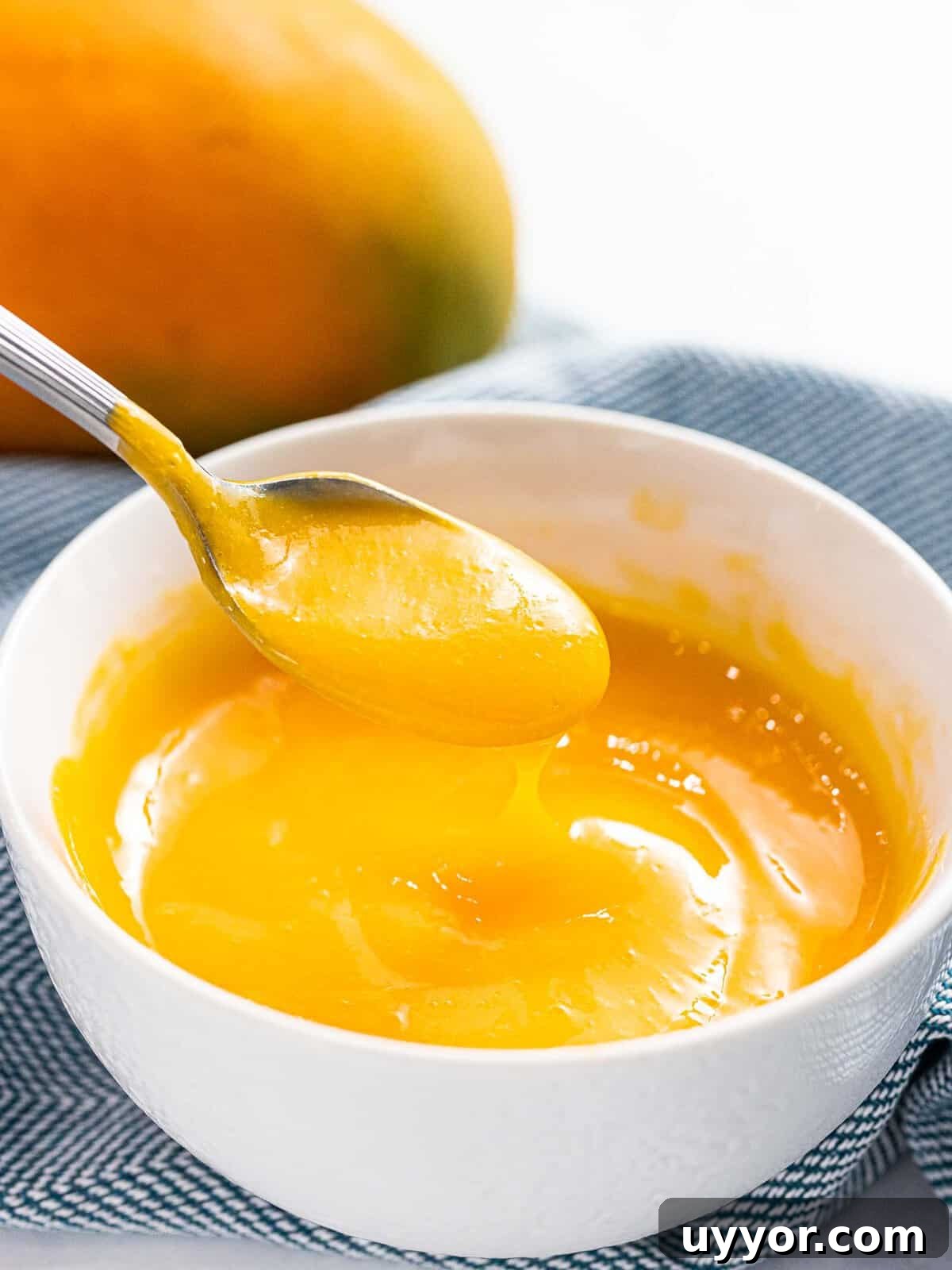 Mango sauce dripping off a spoon.