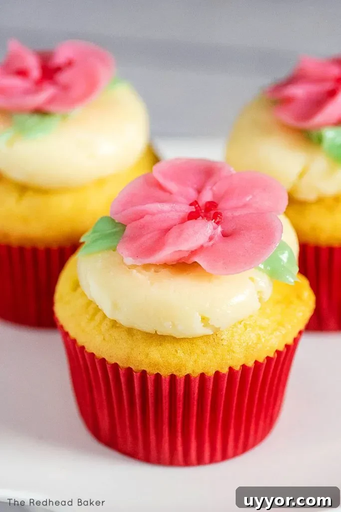 Three cupcakes frosted with swiss buttercream and topped with buttercream cherry blossoms