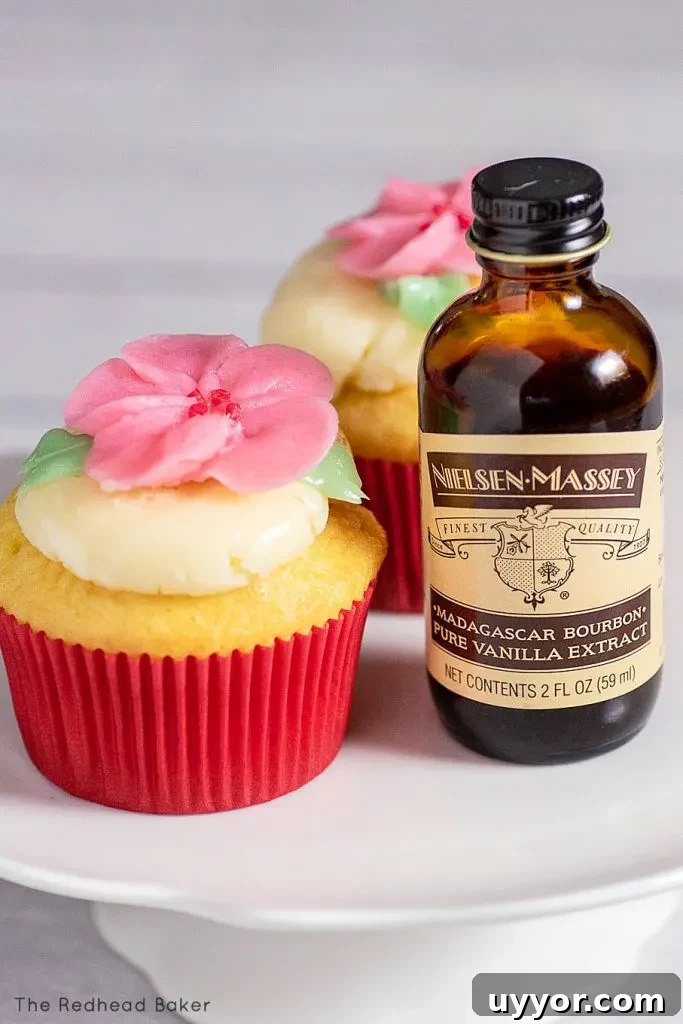 Two cupcakes next to a bottle of Nielsen-Massey vanilla extract