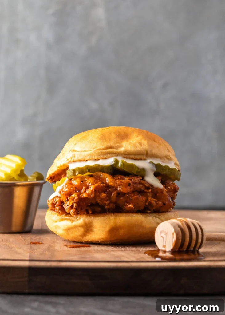 Spicy Honey Chicken Sandwich Recipe for Crispy, Tangy Flavor 2 hot honey chicken sandwich on a cutting board with pickles and honey