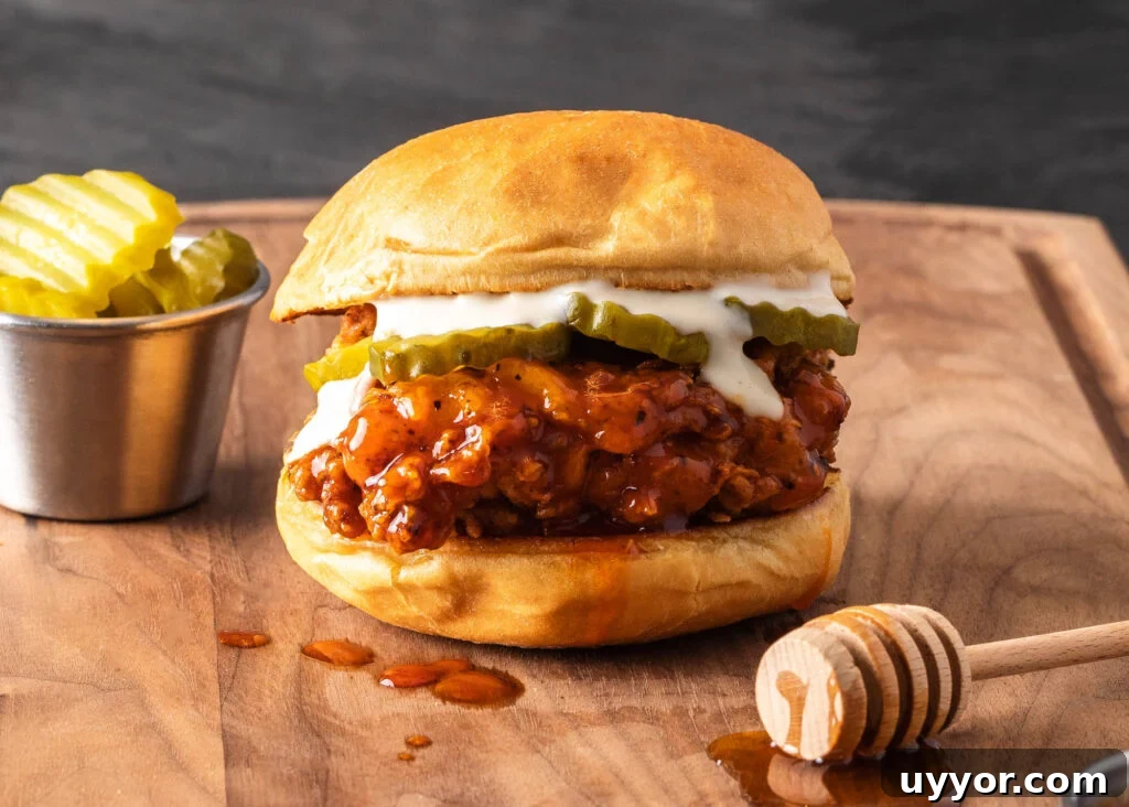 Spicy Honey Chicken Sandwich Recipe for Crispy, Tangy Flavor 3 hot honey chicken sandwich on a cutting board with pickles and honey