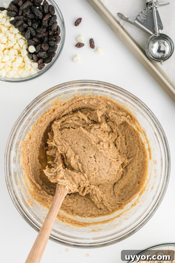 Pumpkin cookie batter with oatmeal, stirred by a wooden spoon.