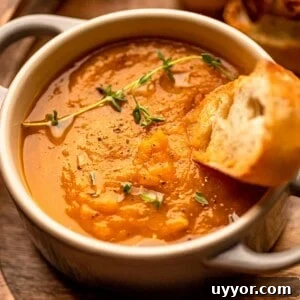 A bowl of pumpkin soup garnished with thyme.