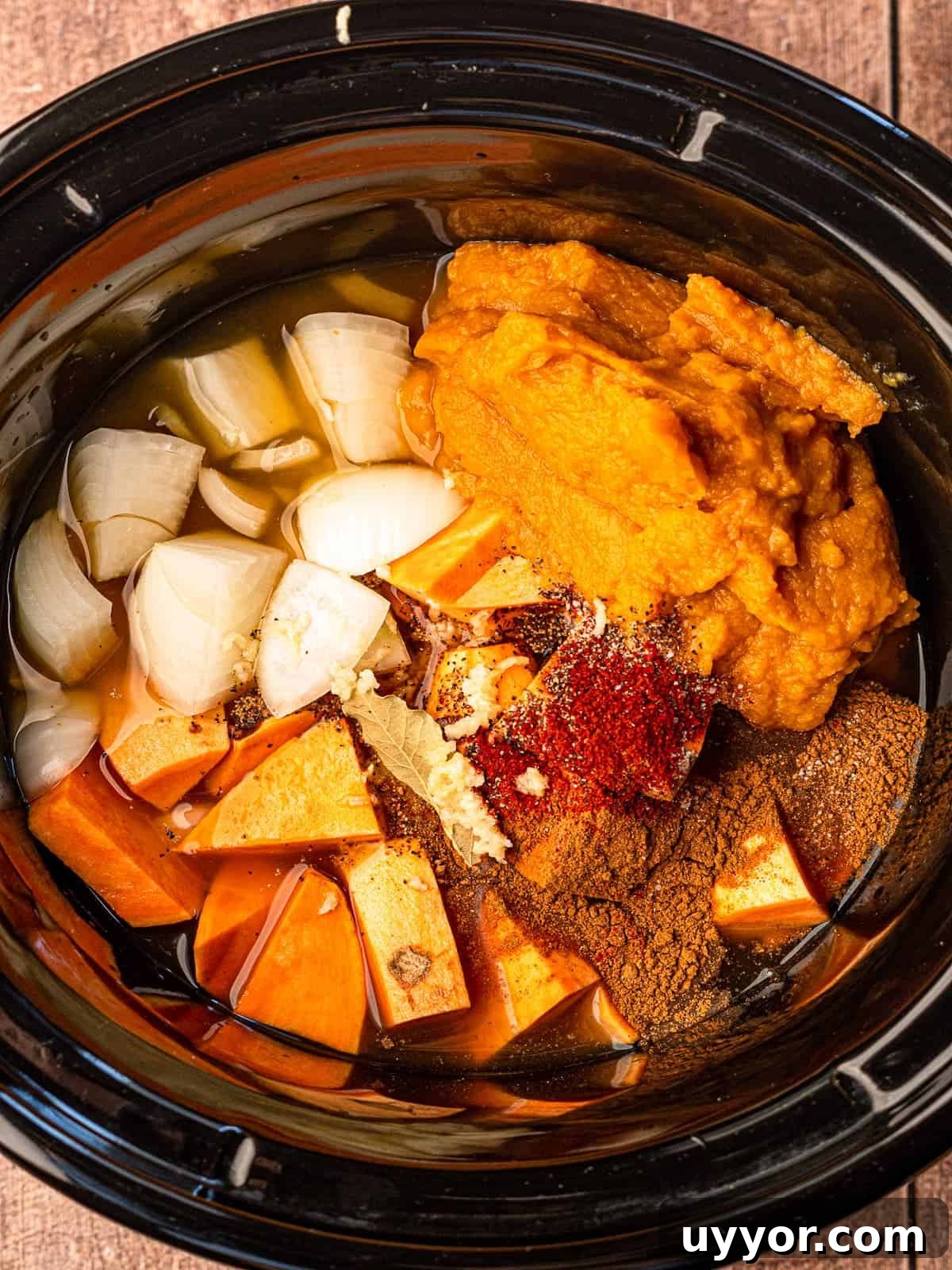 A slow cooker full of ingredients for sweet potato and pumpkin soup.