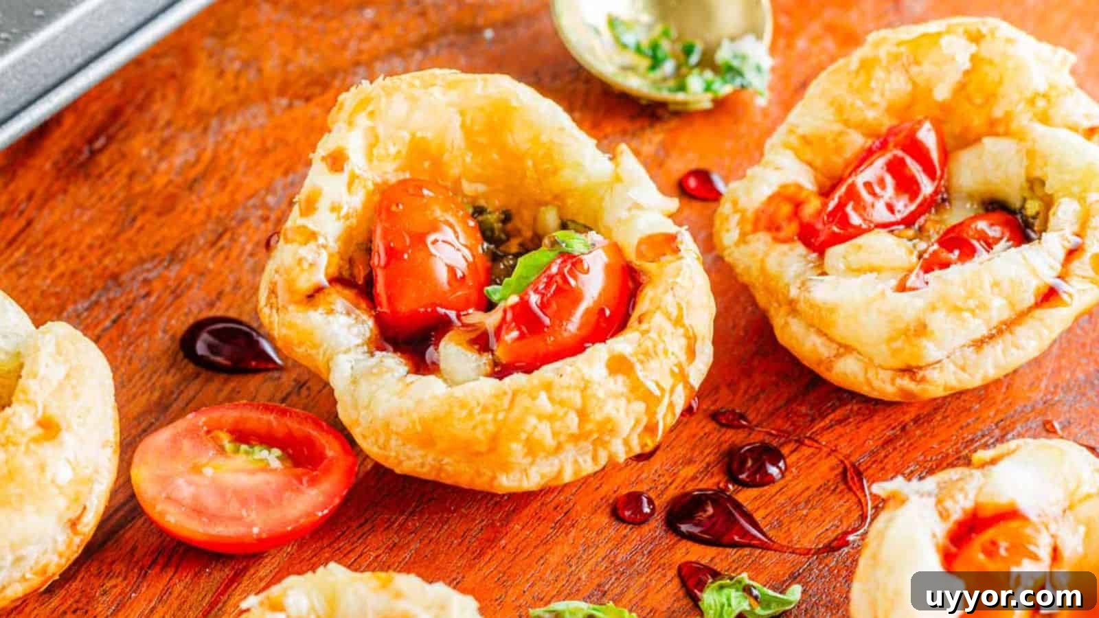 Fresh cherry tomatoes and herbs served in crispy puff pastry cups on a wooden surface.