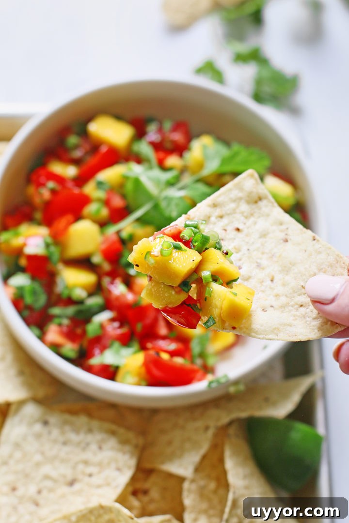 Fresh Mango and Tomato Salsa Recipe for Summer Parties 7 woman dipping a tortilla chip in a bowl of mango salsa