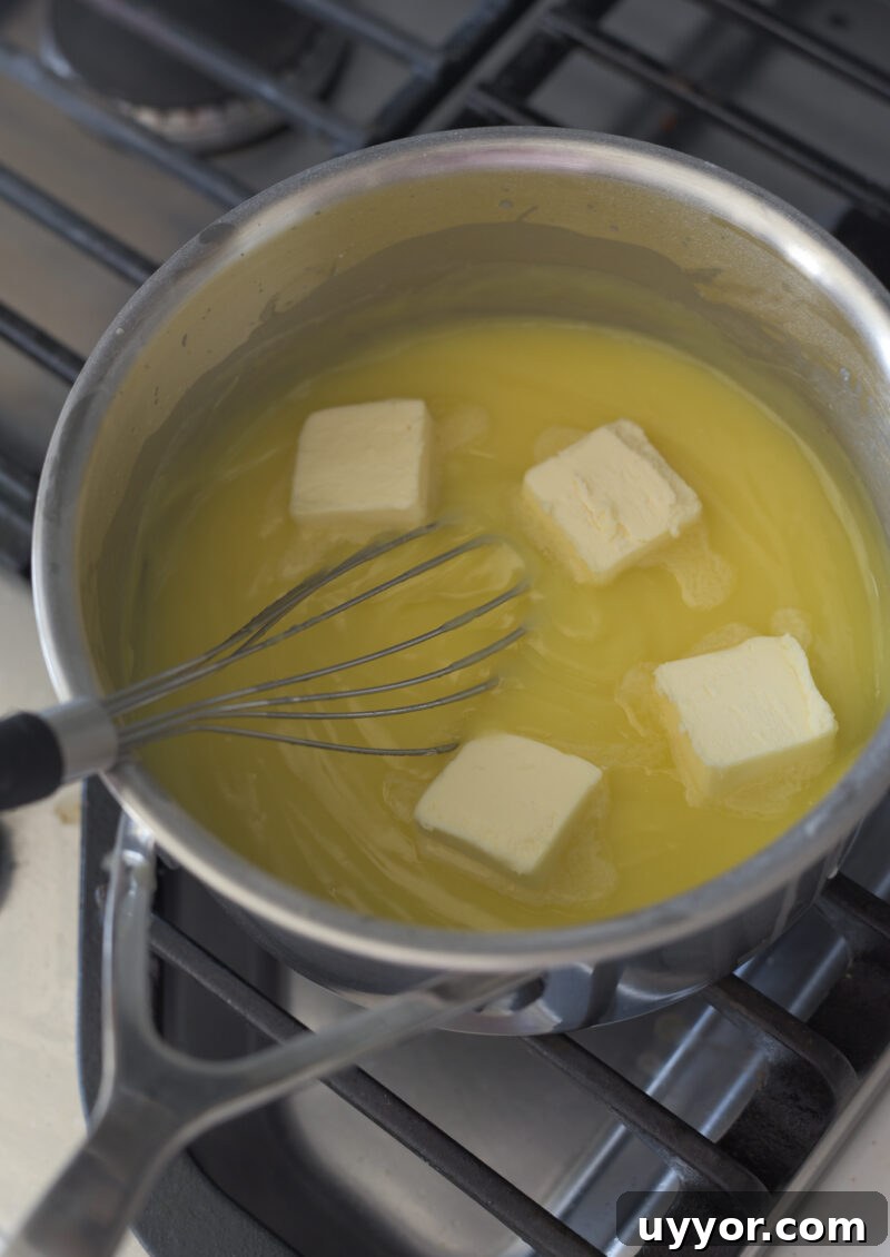 4 pieces of butter is added to lemon custard in a pan.
