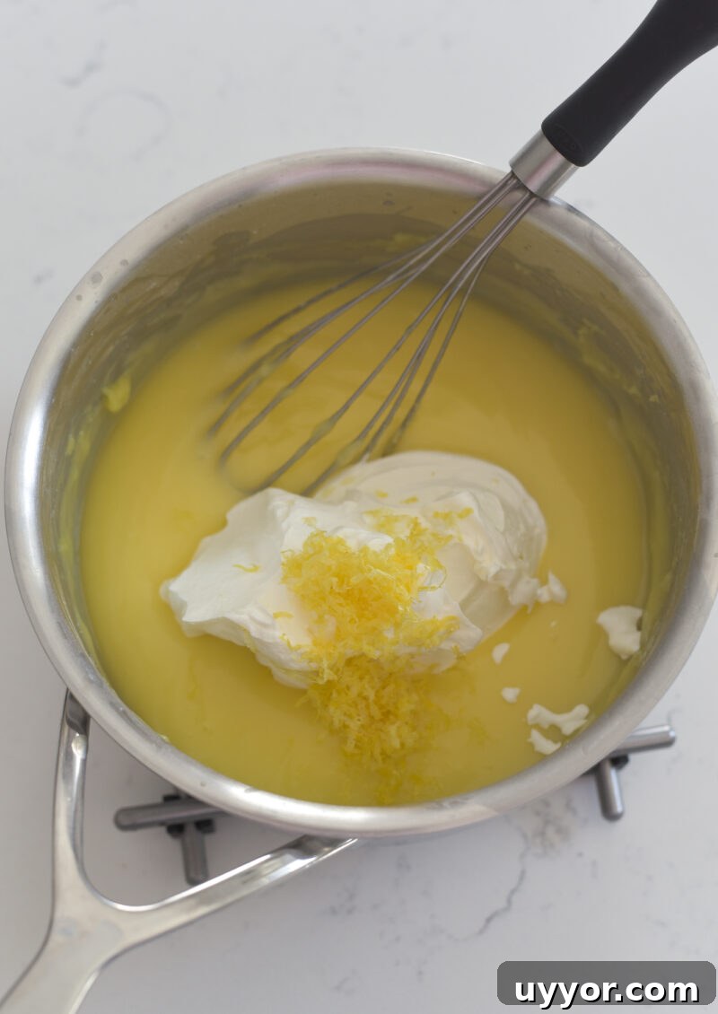 Sour cream and lemon zest are added to a lemon custard in a pan on a cooling rack.