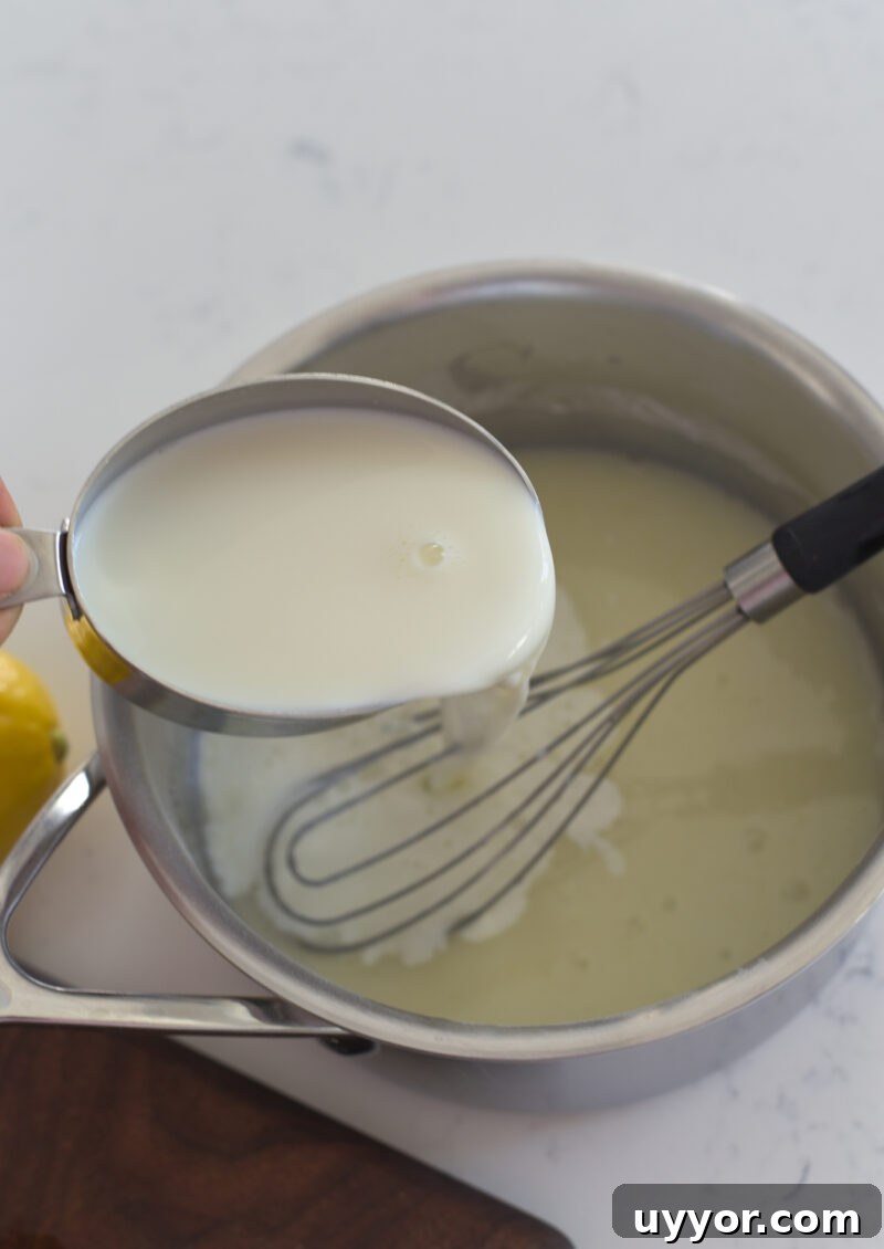 A cup of milk is added to lemon and sugar mixture in a pan.