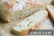 Hearty Ham Bone and Lentil Soup Recipe for Deep Flavor 11 A round loaf of crusty bread with a couple slices of bread on brown parchment paper.