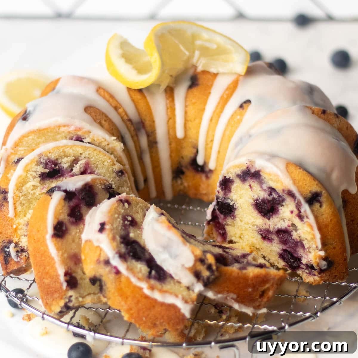 Blueberry Lemon Pound Cake Recipe with Zesty Glaze 2 A recipe for blueberry and lemon pound cake, shown sliced and served on a cooling rack, topped with lemon glaze and fresh blueberries.