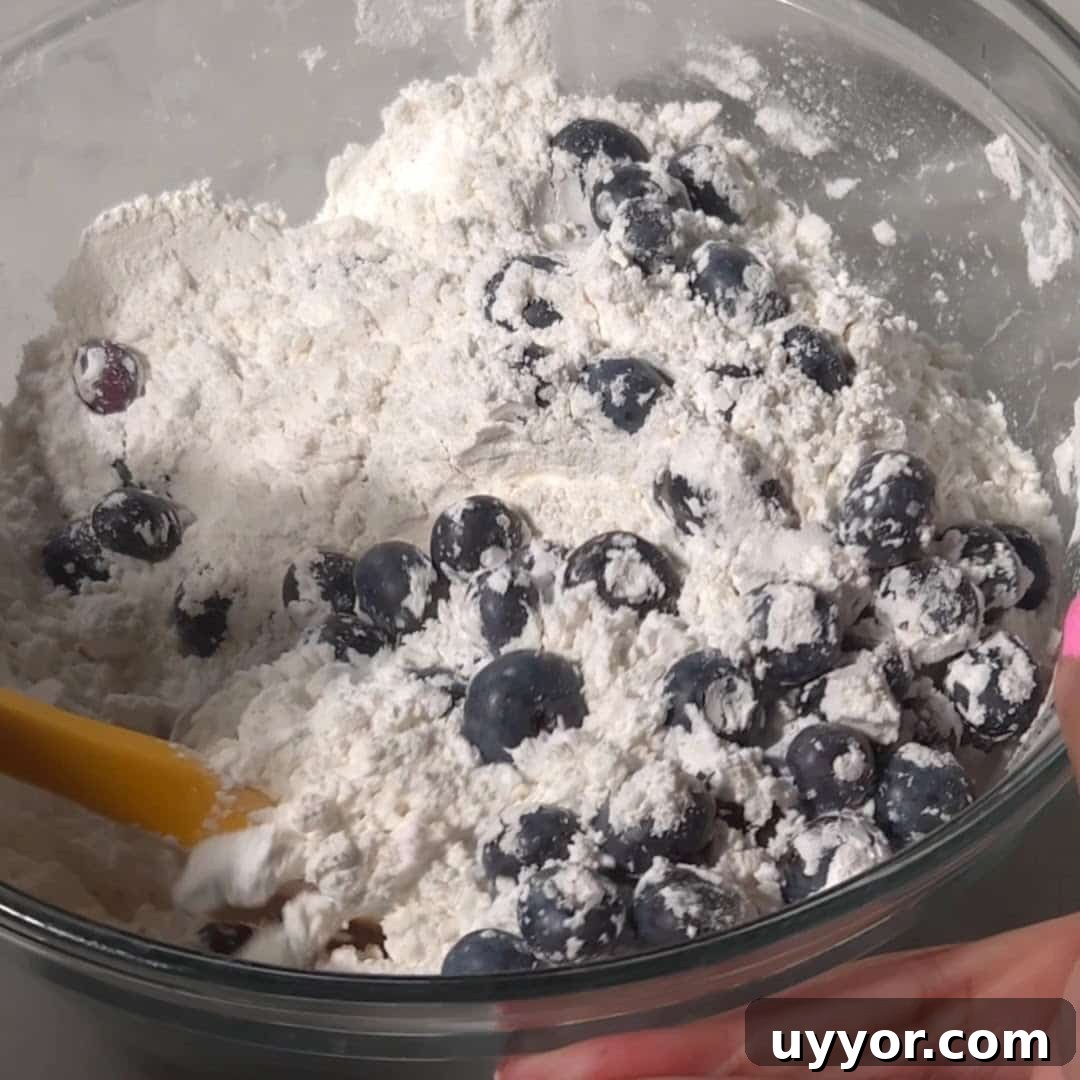 Blueberry Lemon Pound Cake Recipe with Zesty Glaze 11 Fresh blueberries being mixed with flour in a bowl for blueberry and lemon pound cake.