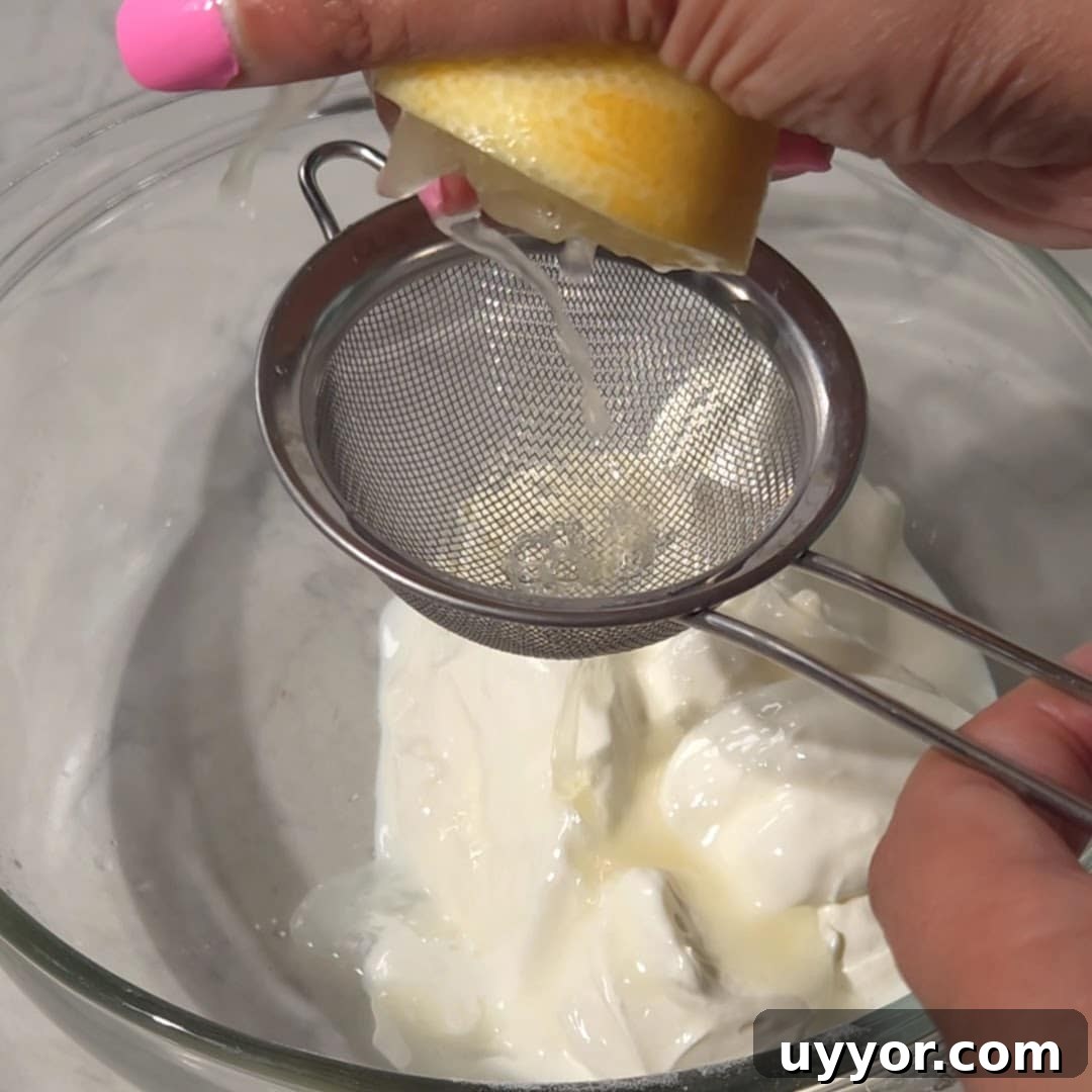 Blueberry Lemon Pound Cake Recipe with Zesty Glaze 12 Squeezing fresh lemon juice through a strainer into a bowl of sour cream for blueberry and lemon pound cake.
