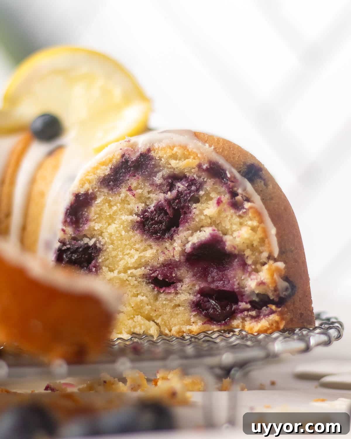Blueberry Lemon Pound Cake Recipe with Zesty Glaze 15 A blueberry and lemon pound cake with lemon glaze, garnished with lemon slices and fresh blueberries, sliced and served on a cooling rack.