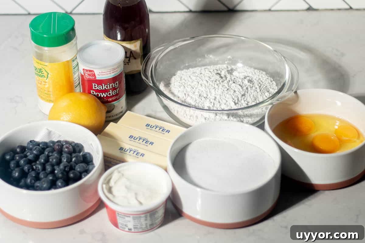 Blueberry Lemon Pound Cake Recipe with Zesty Glaze 5 Ingredients for blueberry and lemon pound cake, including blueberries, lemons, butter, sugar, eggs, flour, baking powder, and vanilla extract, arranged on a kitchen counter.