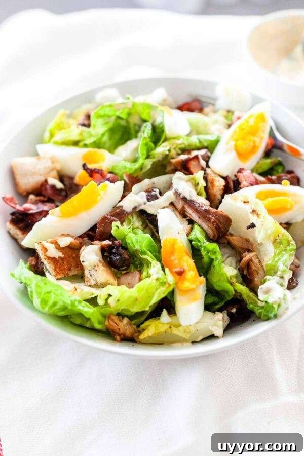Classic Chicken Caesar Salad Recipe with Crispy Croutons 5 Chicken caesar salad topped with egg served in a white bowl.