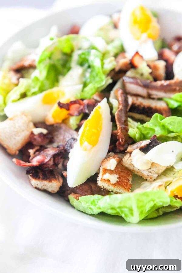 Classic Chicken Caesar Salad Recipe with Crispy Croutons 6 Close up of a homemade caesar salad with chicken, egg, lettuce, anchovies, croutons and crispy bacon.